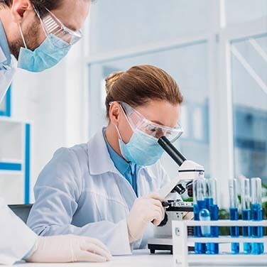 Safety Lab Scientists looking through a microscop